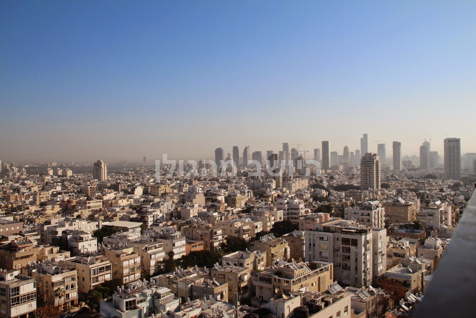 גגות העיר ומגדלים רחוקים תחת מרחב של שמים כחולים
