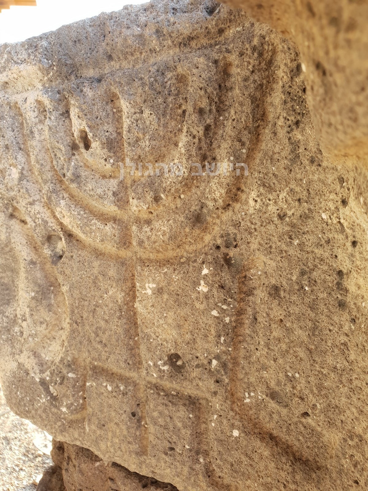 תבליט מנורה חקוק באבן בבית הכנסת אום אל־קנטיר בעין קשתות